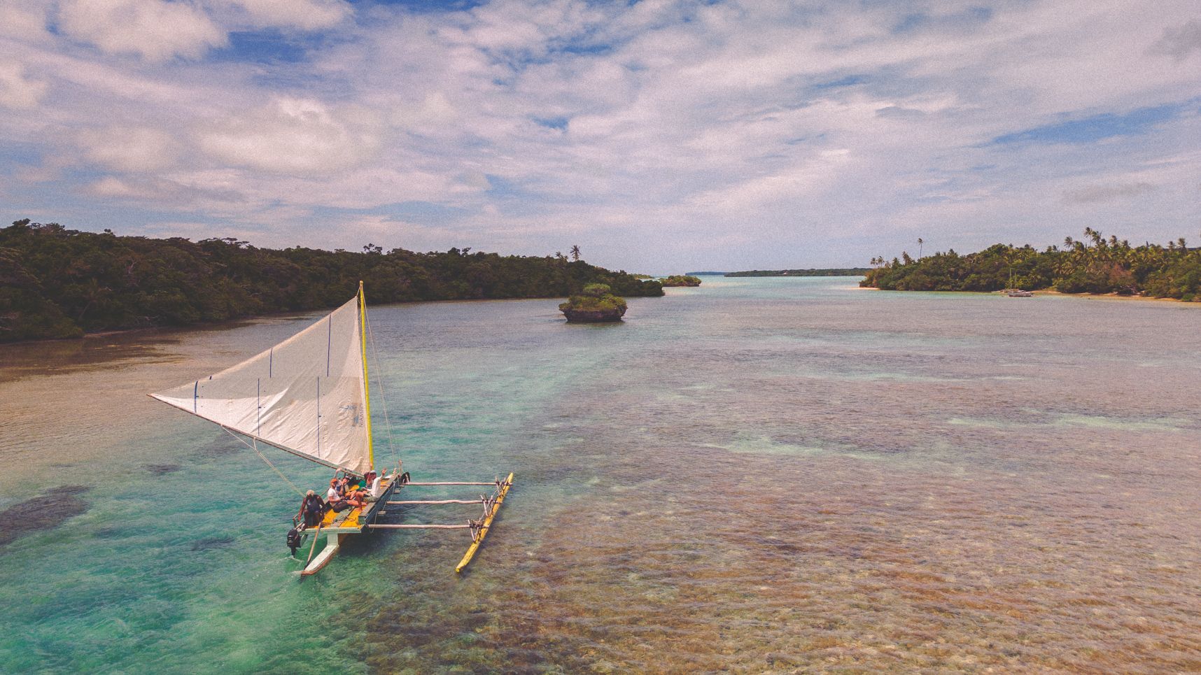 Pirogue dans la baie d'Upi en premier plan, L'eau est turquoise. En arrière plan la sortie du canal et la mer