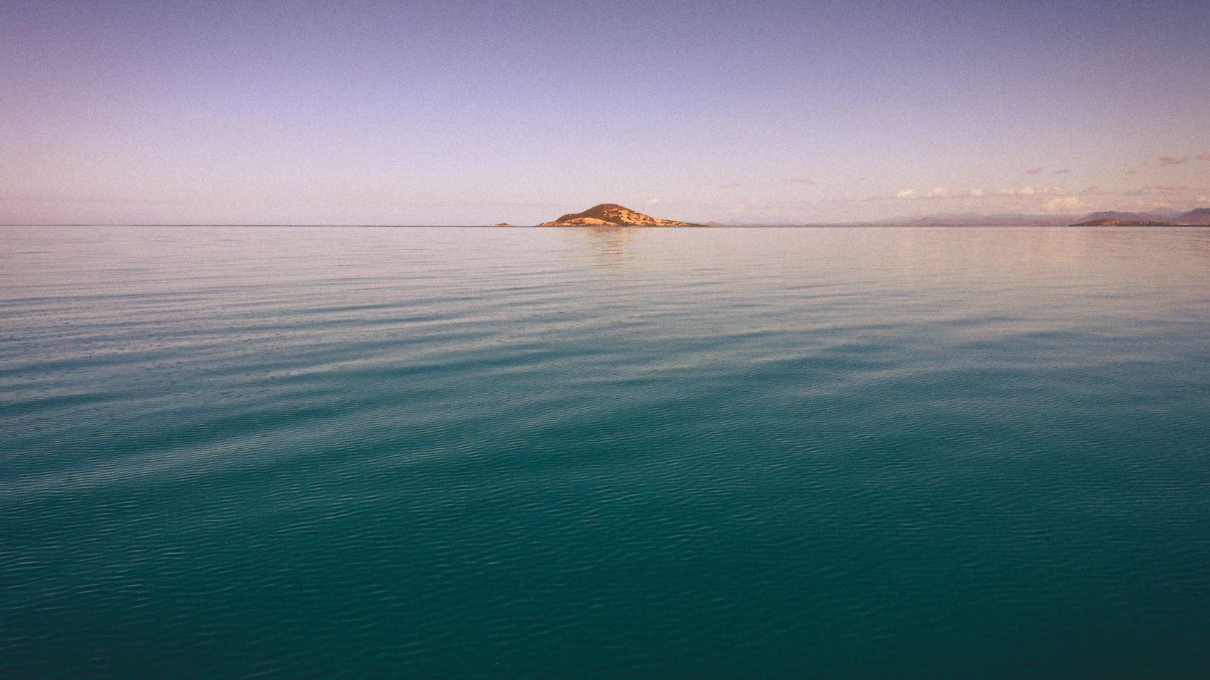 Plan d'eau glassy, petite Coline sur l'horizon, les nuages reflètent sur l'eau