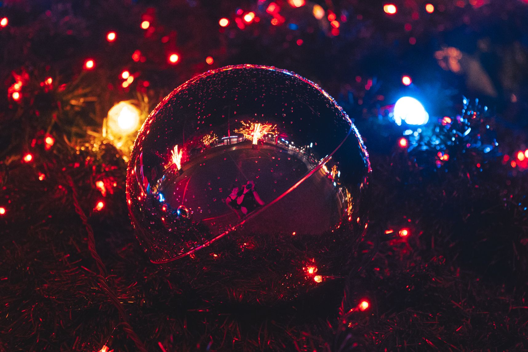 Vue rapprochée du sapin de Noël de Nouméa. Les illuminations reflètent dans la boule ainsi que le photographe et sa chérie