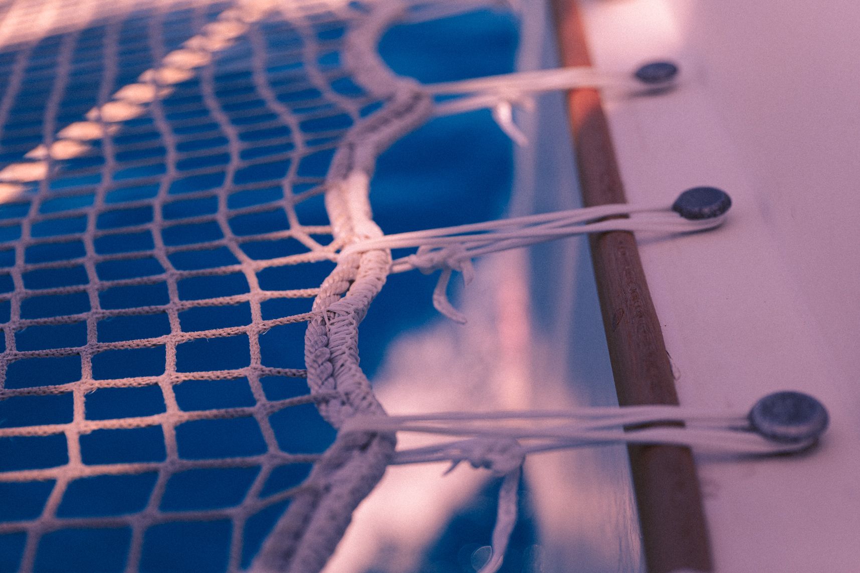 Gros plan sur le coté d'un filet de catamaran. Les attaches d'un coté, en dessous du filet le bleu de la mer