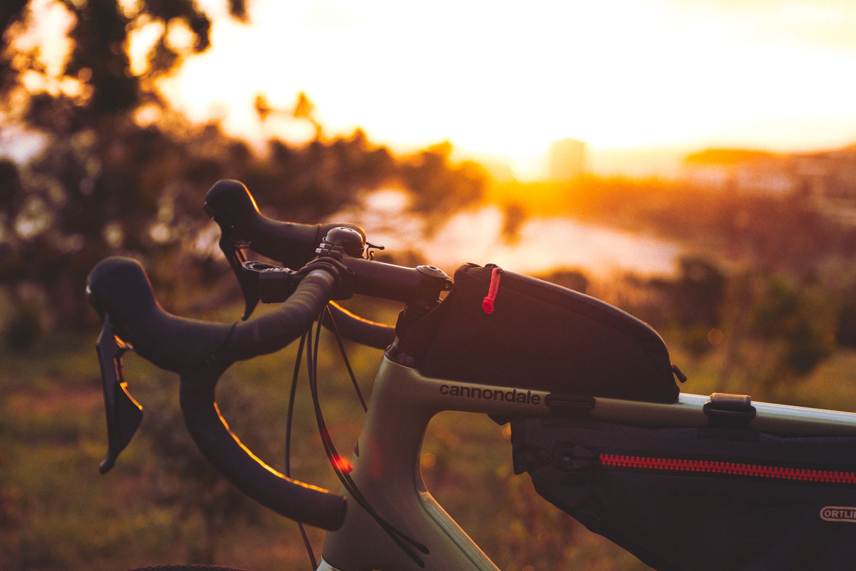 Gros plan de côté sur le guidon du vélo gravel. Derrière en arrière plan le coucher de soleil et Nouméa.