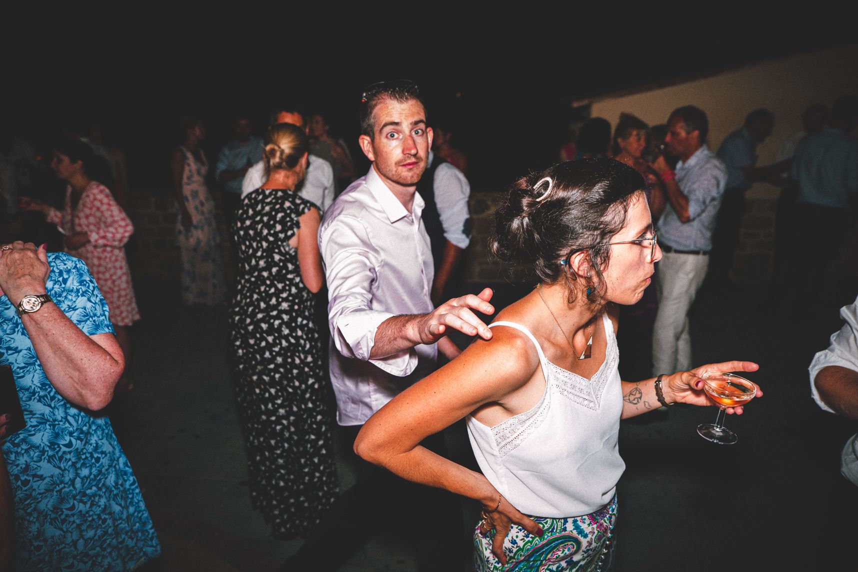 Une foule en petit groupe en train de discuter un verre de champagne à la main. Une personne tape sur l'épaule opposée d'où elle passe