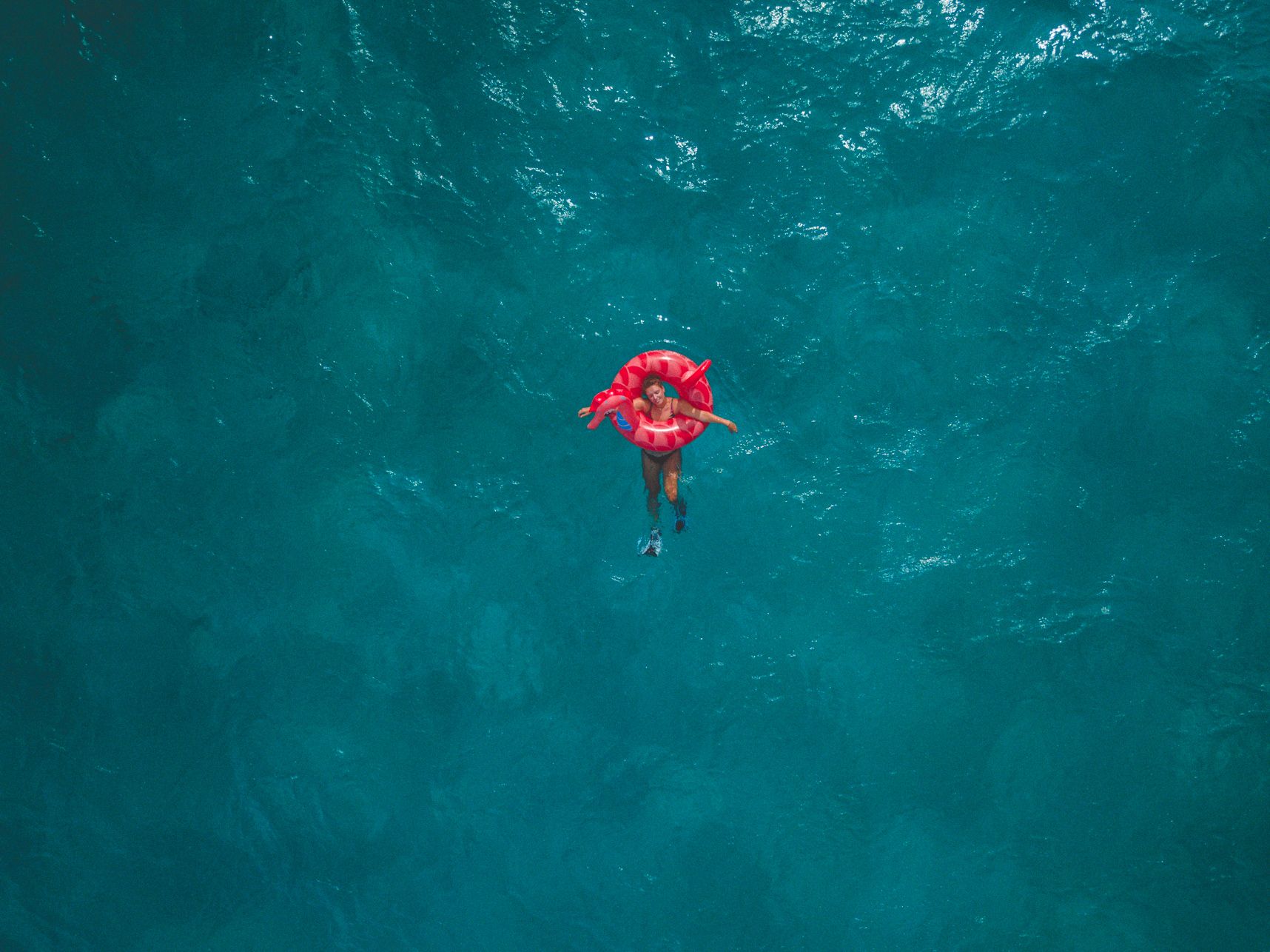 Vue de drone, la personne dans la bouée rose est toute seule dans l'immensité de la mer