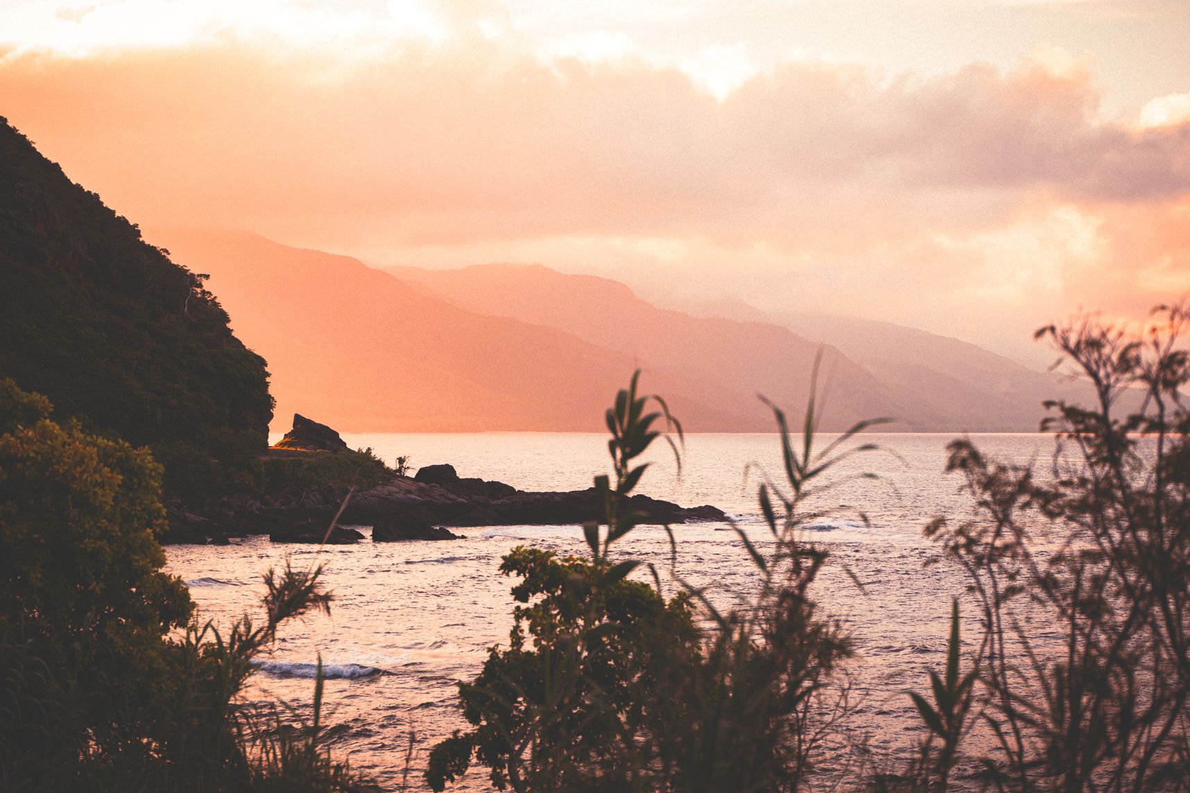 Sur la côte Est de la nouvelle calédonie, la route est prise entre les montagnes et la mer. Derrière le virage le coucher de soleil se cache