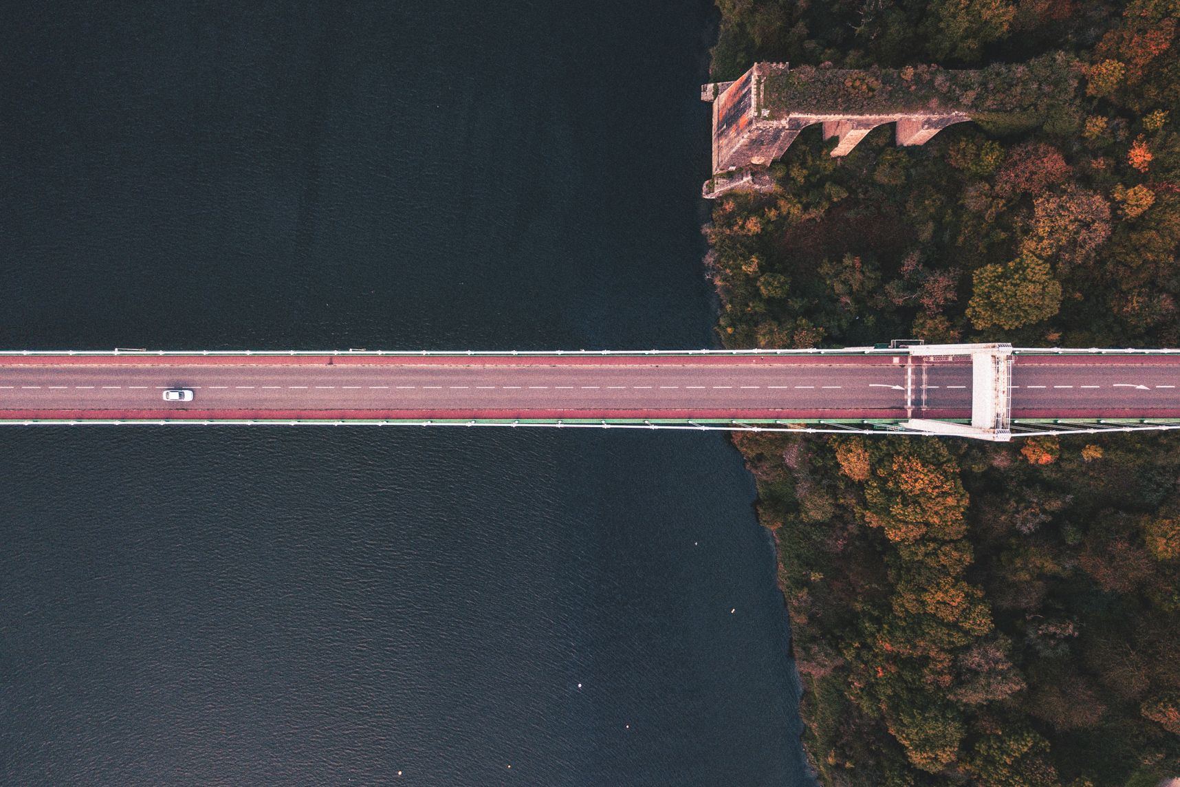 La moitié du pont de la Roche-Bernard vue du dessus par un drone. Une seule voiture y circule, elle avance vers la forêt