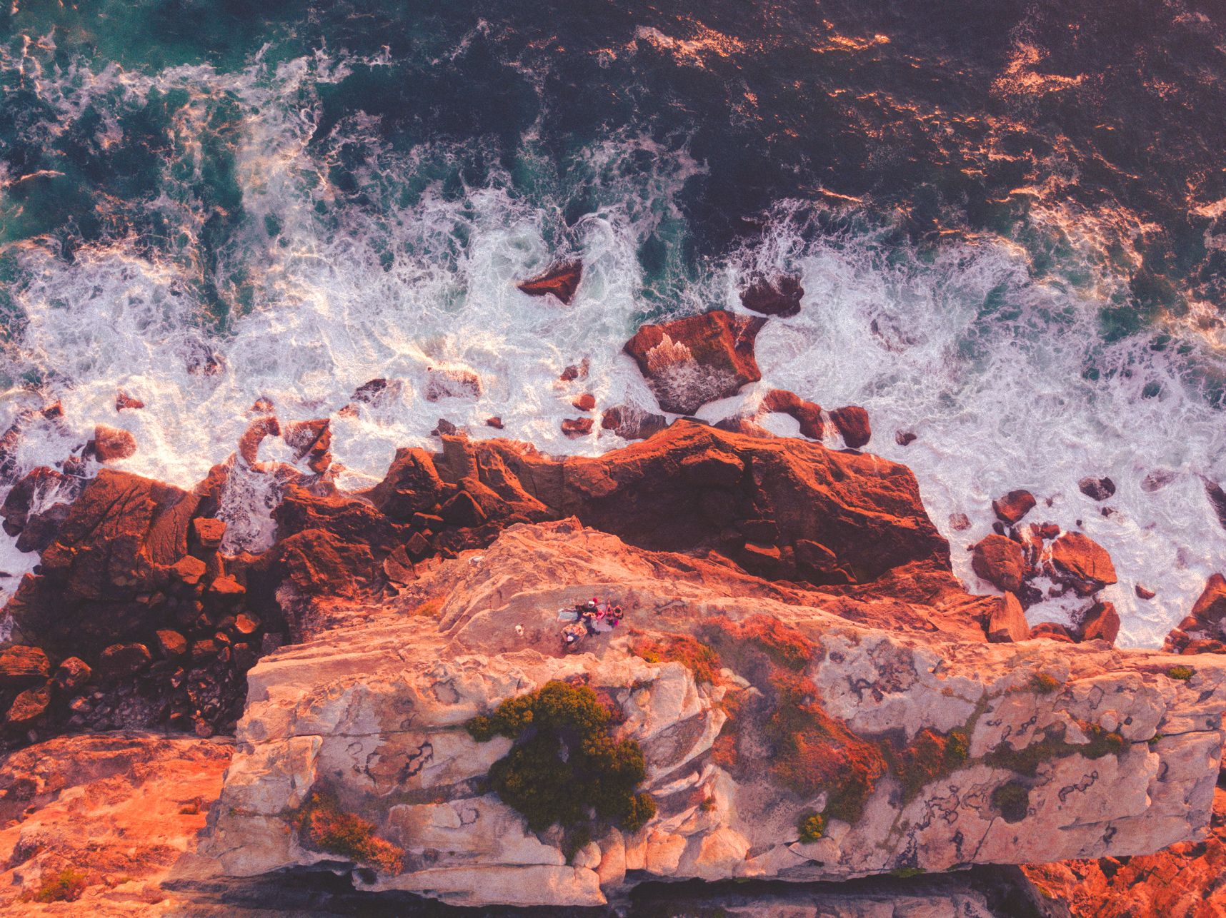 Vue du haut des falaises de North Bondi au lever de soleil. Des gens y admirent le spectacle au bord du précipice