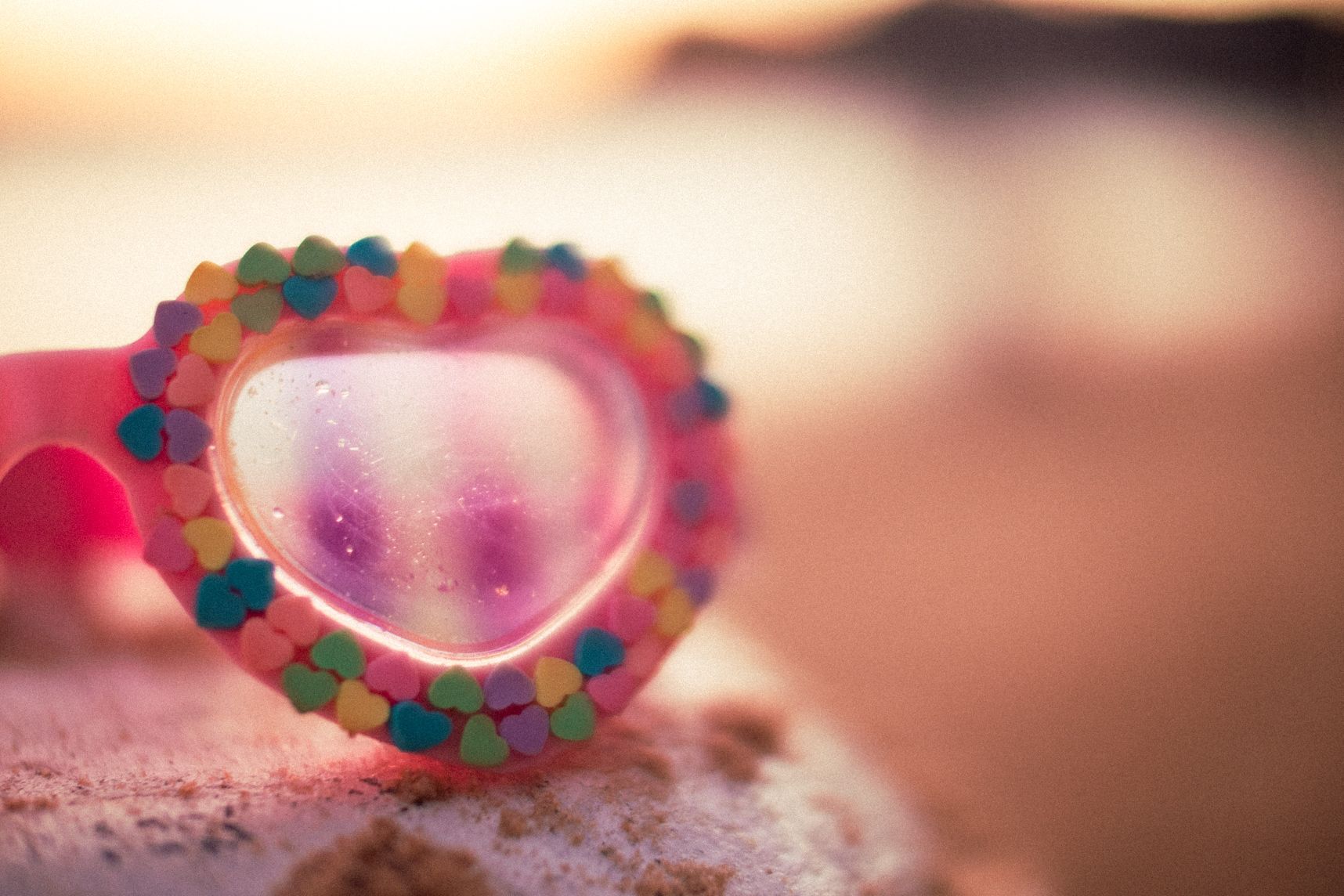 Lunettes de piscine en forme de coeur avec en fond flou le couché de soleil