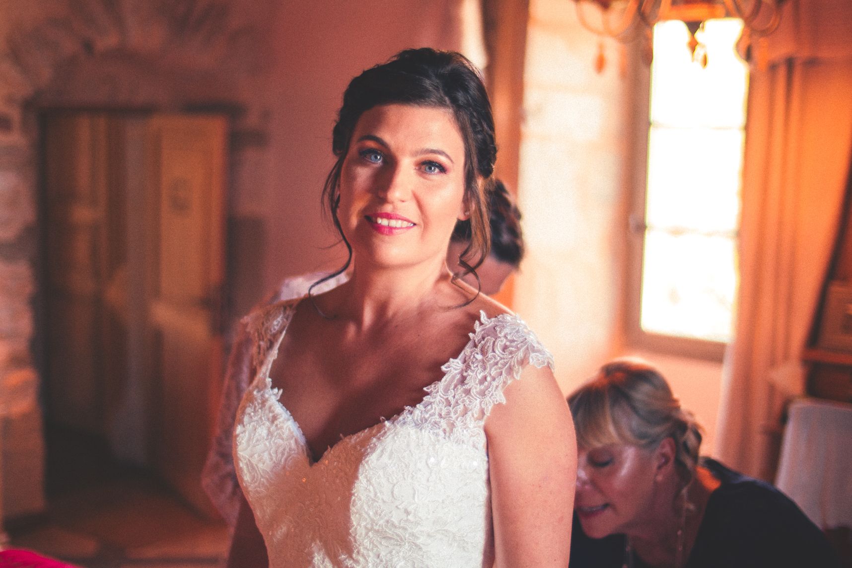 La jeune mariée avec le grand sourire lors de l'enfilage de la robe