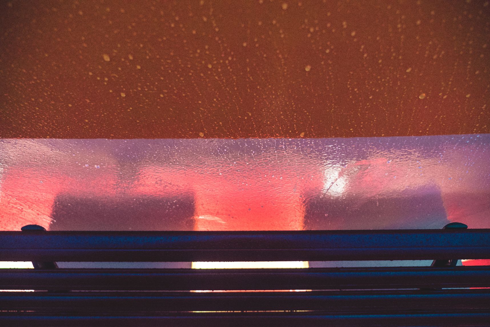 Sur le ferry de Sydney, une lumière orange sort du dessous du banc. La pluie ruisselle sur le mur