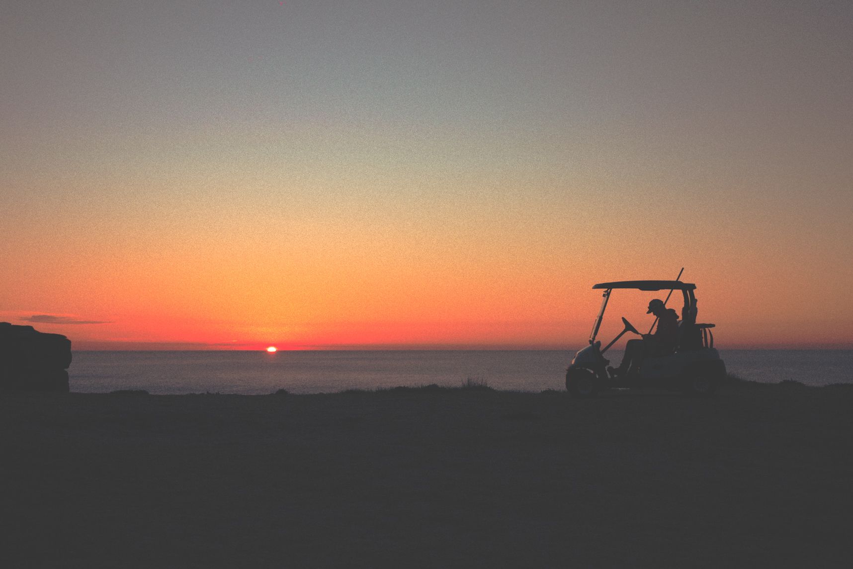 L'employé du golf de Bondi fait une pause pour le lever de soleil. Il a arrêté sa voiturette électrique juste au bord de la falaise