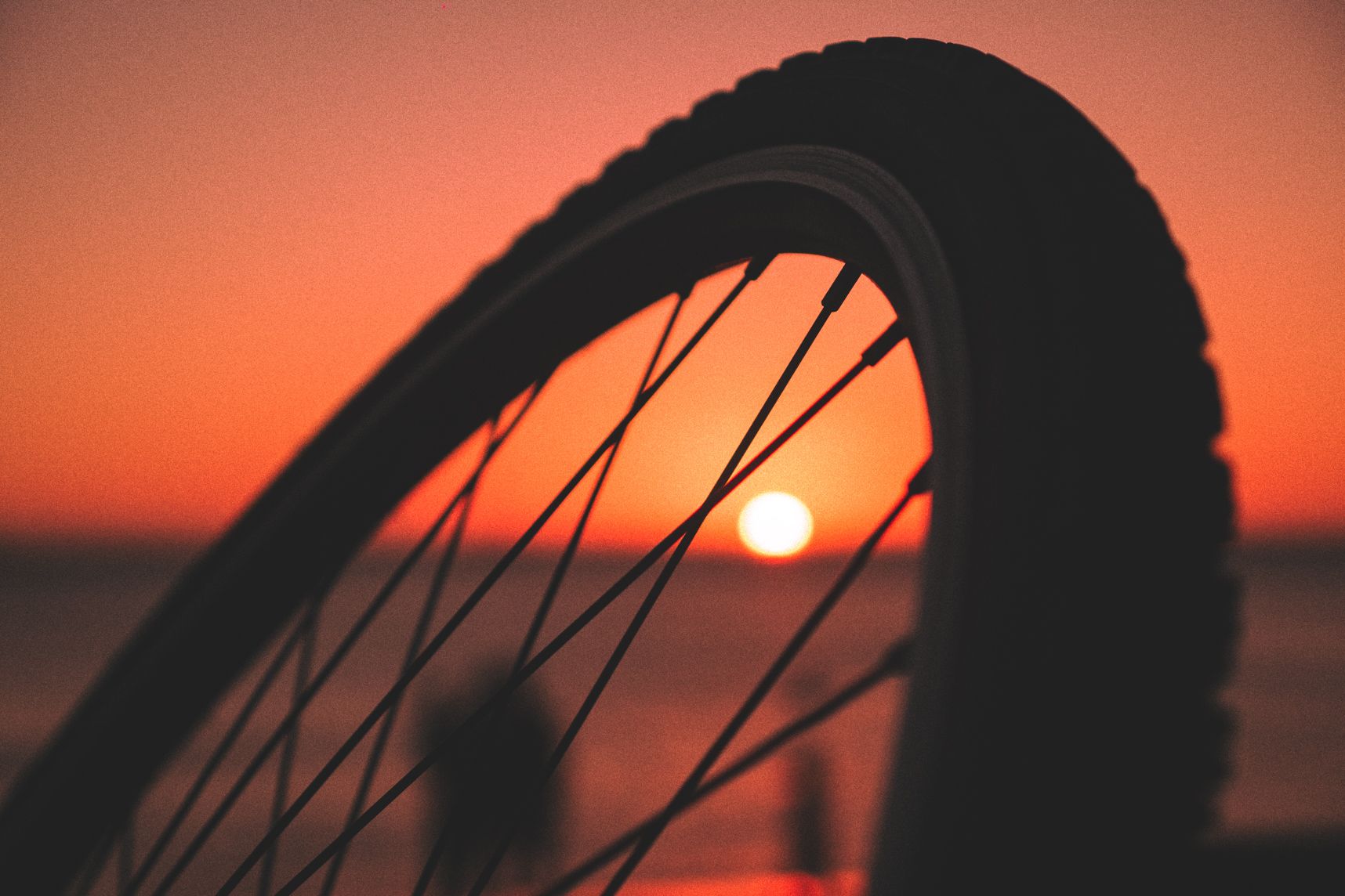 les rayons de la roue de vélo en premier plan, le coucher de soleil avec effet bokeh en arrière plan
