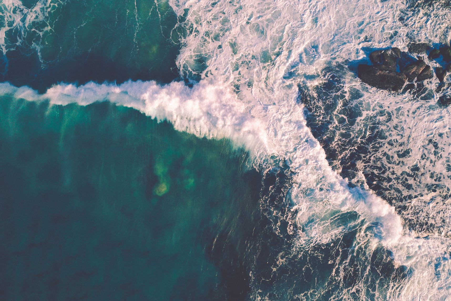 Vue de drone des vagues en train de se dérouler dans une mer turquoise 