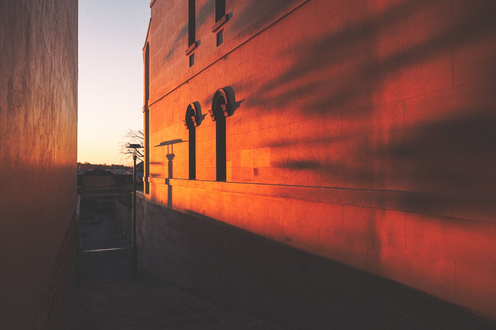 Sur la colline de The Rocks, le coucher de soleil éclair les murs de la maison. Les ombres allongées ont l'air de démons