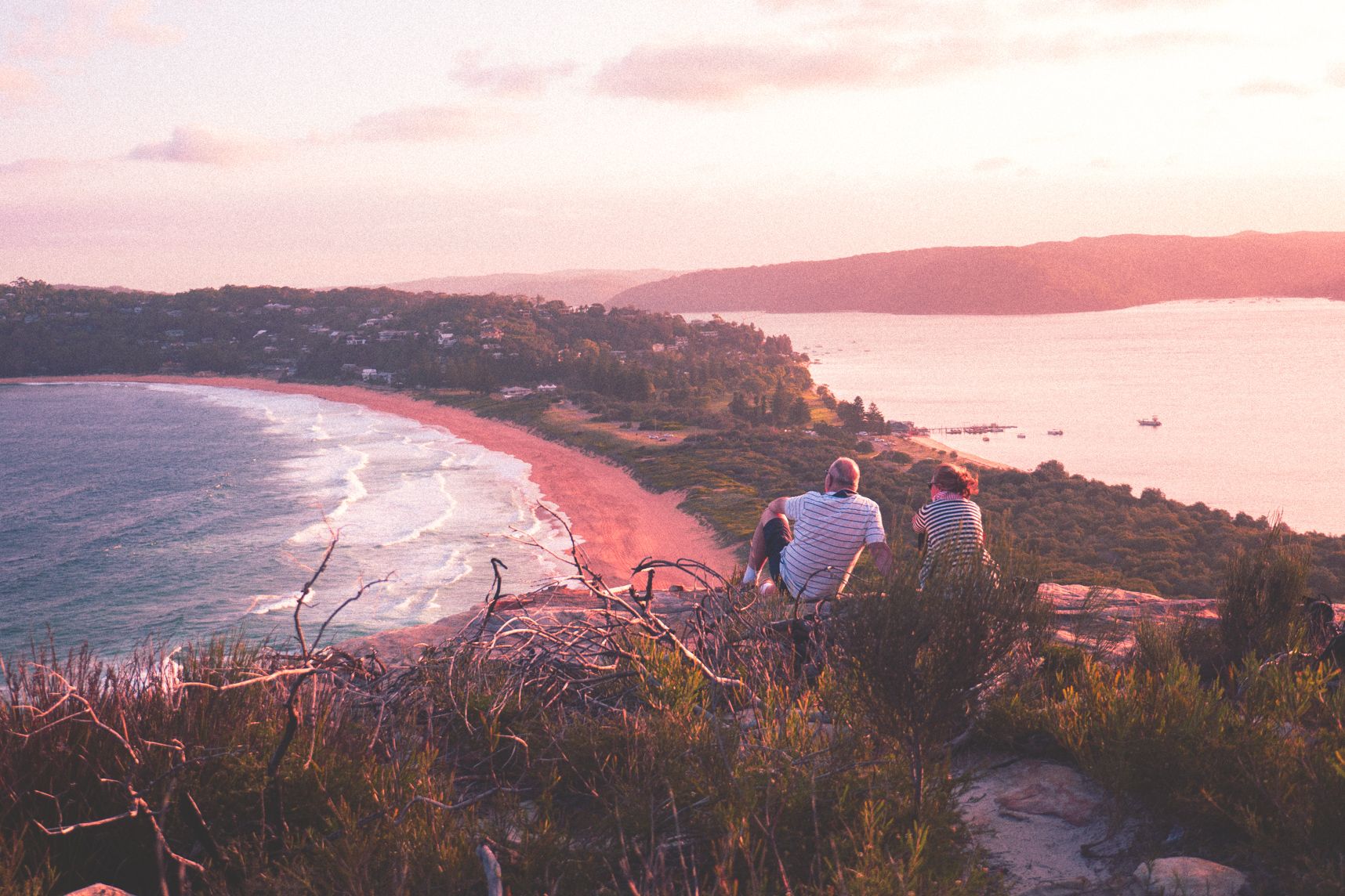 Assis sur un rocher, les gens admirent le paysage de Palm Beach au coucher de soleil