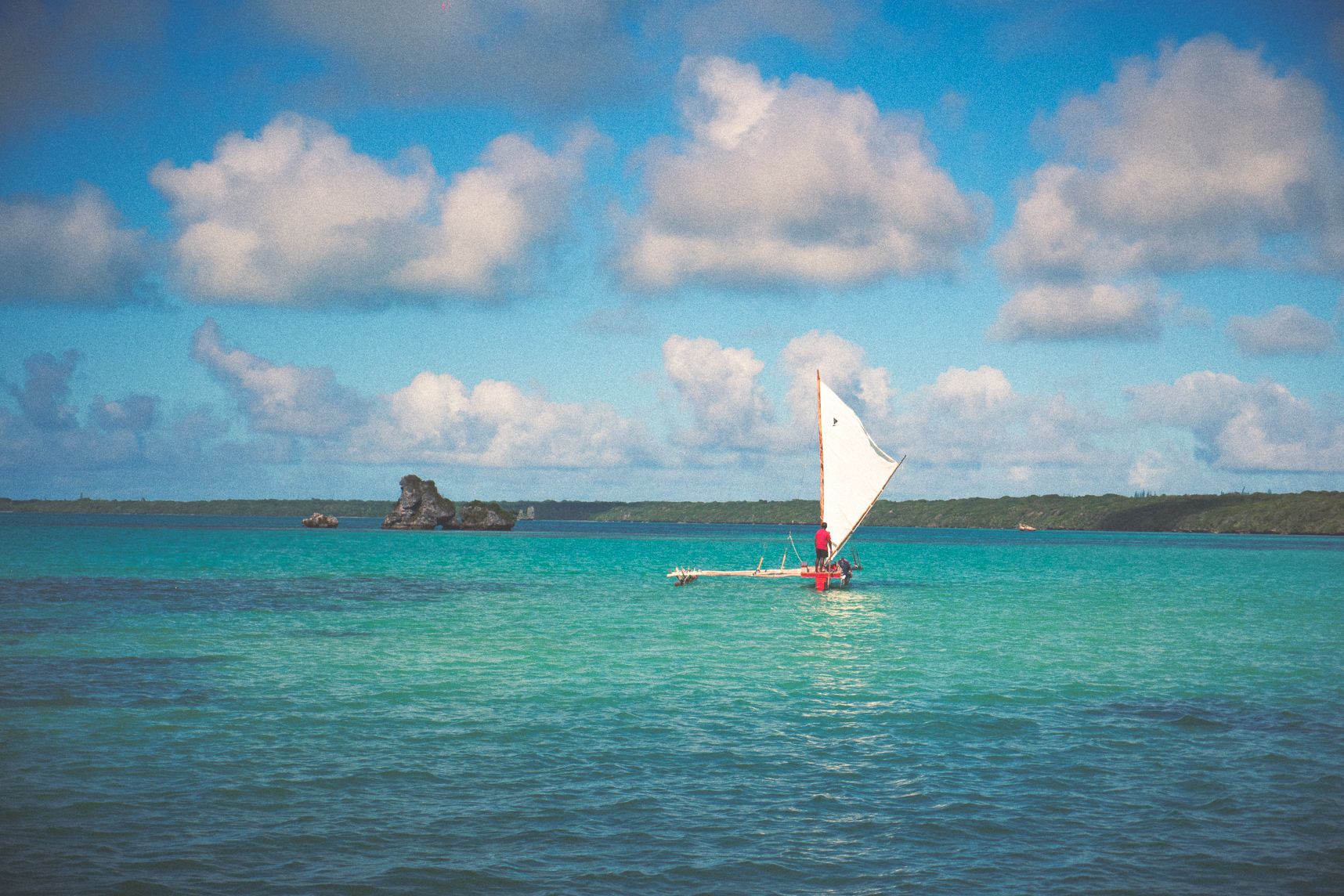 Seul dans la baie d'Upi, la pirogue repart à son quai d'attache. L'eau est turquoise