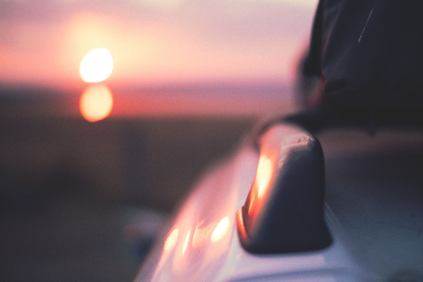 Le coucher de soleil, flou en arrière plan, reflète sur le toit et la barre de toit de la voiture