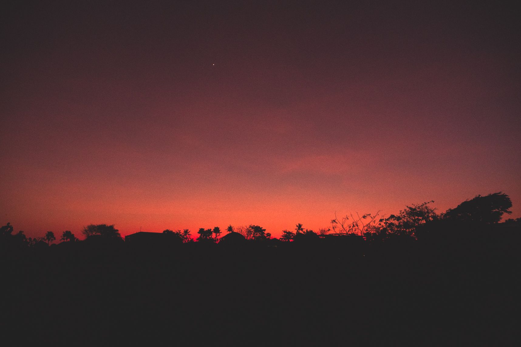 Le soleil s'est couché, le ciel est toujours orange, les cocotiers dessinent leur silhouette dans l'ombre