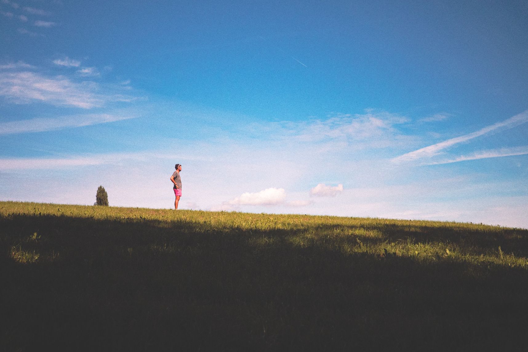 Un personne est juste sur la ligne d'horizon de la butte d'herbe. Derrière le ciel est bleu