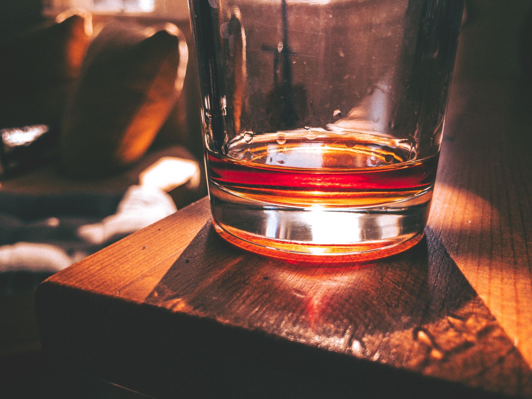 Le soleil reflète dans le verre de Cognac. La table en bois et le canapé beige donne un ton orangé à la photo