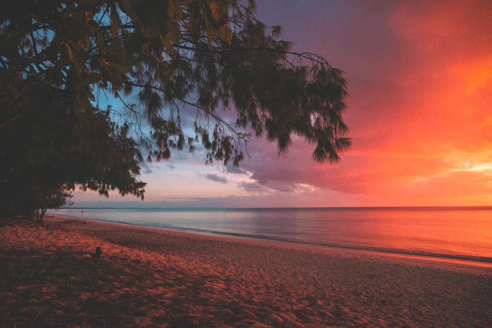À droite le coucher de soleil colore le nuage d'orange. À gauche la nuit tombe après la pluie. Le tout vu de la plage paradisiaque d'Ouvéa