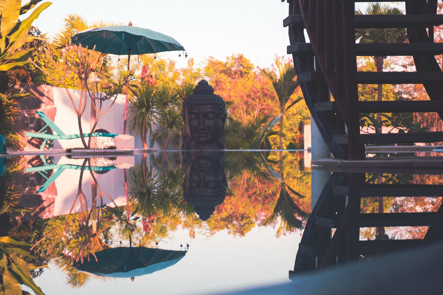 Au lever de soleil la statue de bouddha les yeux fermés reste zen. Le reflet sur la piscine au calme plat amplifie l'atmosphère zen